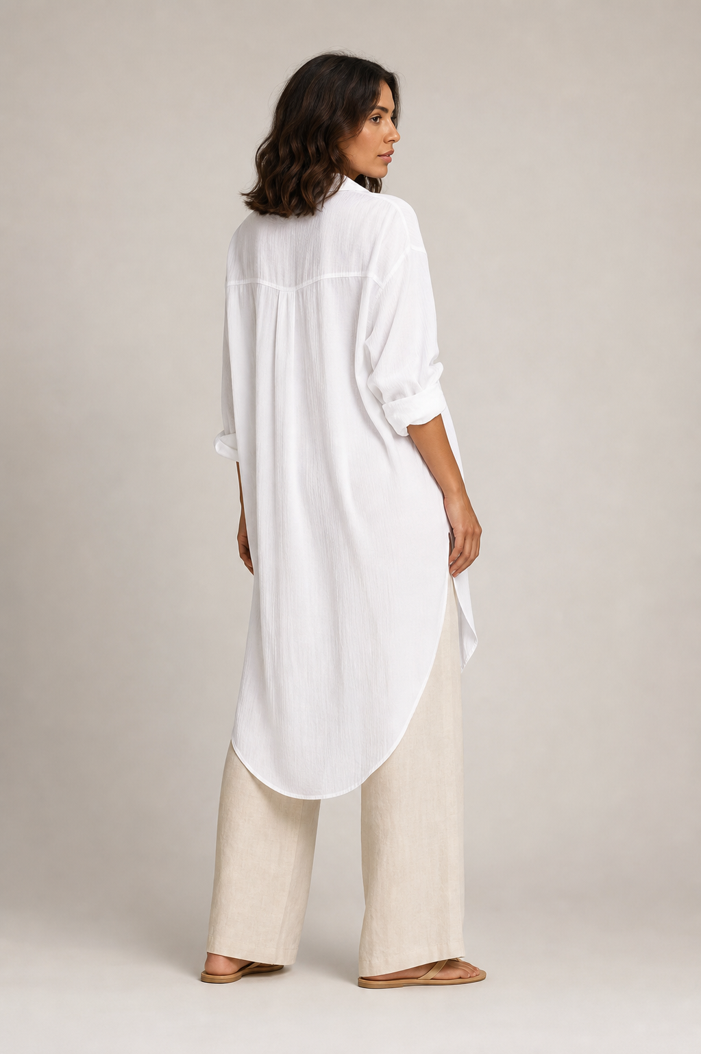 Camisa blanca larga con hombros caídos y bajo redondeado, vista trasera.