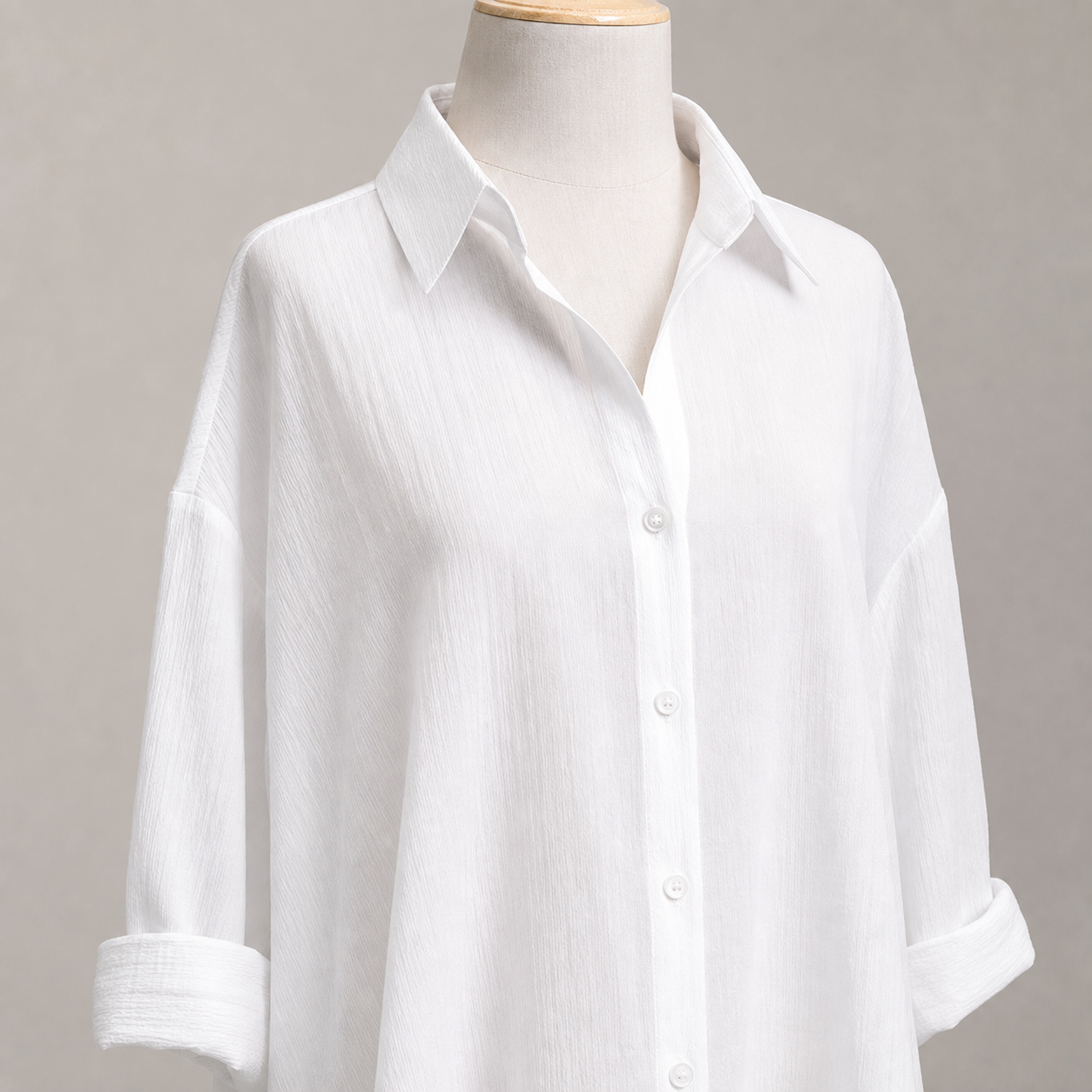 Detalle del cuello, los botones, las mangas y la textura de la camisa blanca.