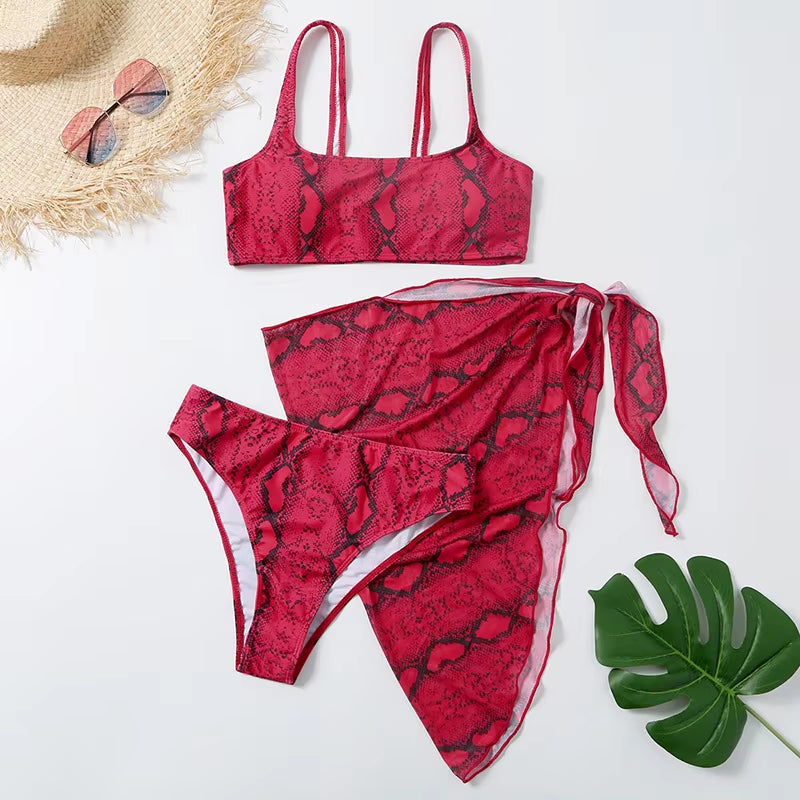 Bikini de tres piezas rojo con estampado de serpiente y pareo a juego.