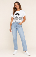 Mujer con camiseta blanca de cerezas plateadas y vaqueros claros